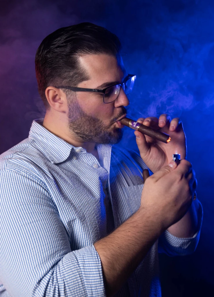 Zachary Nikollaj lighting a cigar